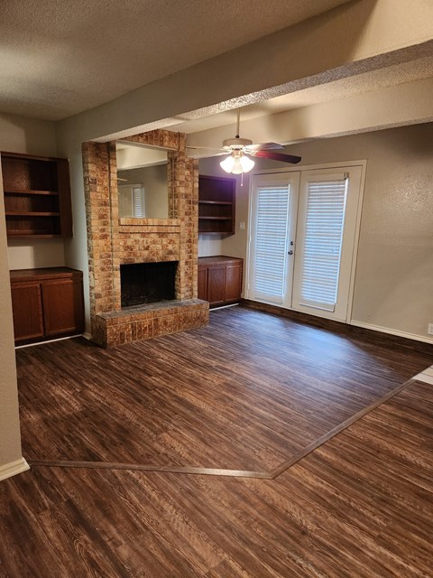 an empty living room with a fireplace and a ceiling fan